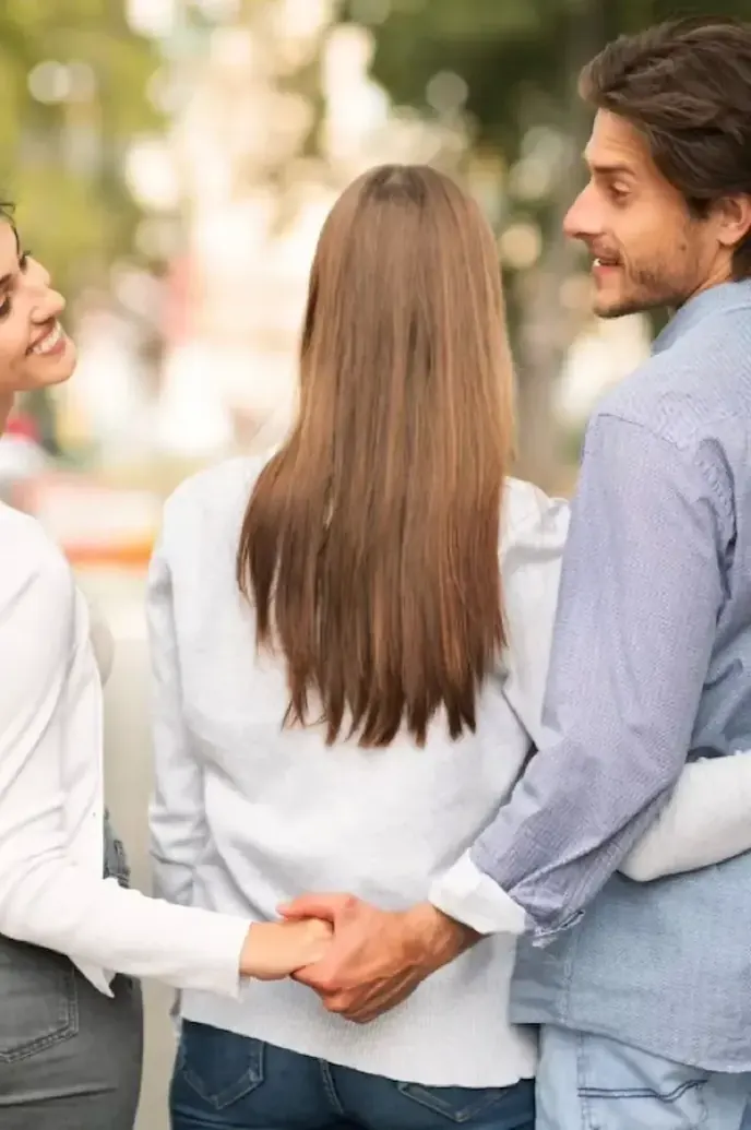 Pareja caminando mientras una tercera persona camina cerca, representando distancia emocional